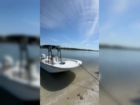 A sleek speedboat anchored on a sandy shore, surrounded by calm waters and clear skies, perfect for a day of relaxation on the water.