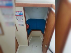 Interior view of a cozy cabin space on a boat, featuring blue seating and safety equipment, perfect for relaxing during trips.