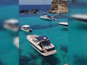 A lively scene featuring a group enjoying a sunny day on a boat in stunning turquoise waters, perfect for swimming and relaxation in a picturesque setting.