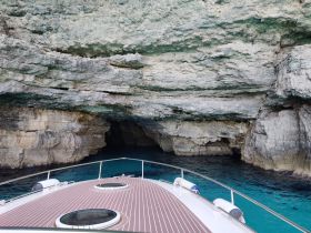 A stunning view from the bow of a boat approaching a rocky cave entrance, showcasing the beautiful turquoise waters and unique geological formations.