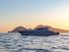 A stunning yacht glides through calm waters at sunset, framed by distant mountains — perfect for luxury cruising and scenic adventures.