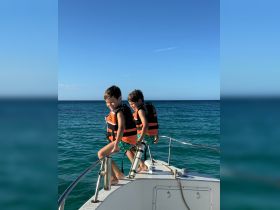 Two young boys enjoy a playful moment on the bow of a boat, wearing life jackets and ready for adventure on the water.