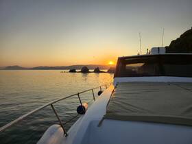 A serene sunset view from the deck of a yacht, showcasing the tranquil waters and distant hills — perfect for evening cruises and relaxation on the water.