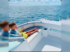 A young boy relaxes on the seating area of a boat, enjoying the serene ocean view — perfect for family outings and adventures on the water.