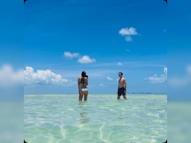 A couple enjoys a sunny day at the beach, capturing memories in the shallow waters — perfect for romantic getaways and photography enthusiasts.