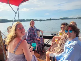 A cheerful group enjoys drinks on a pontoon boat, capturing the essence of a fun day on the water with friends.