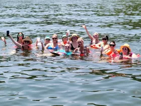 A lively group of friends enjoys a fun day in the water, celebrating with drinks and laughter — perfect for summer outings and memorable gatherings.