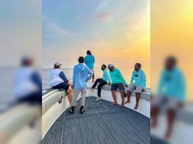 A group of friends enjoys a beautiful sunset aboard a boat, creating memorable moments on the water.