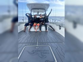 A group of friends enjoys a fun day on a fishing boat, striking playful poses against the backdrop of the ocean — perfect for adventure seekers and fishing enthusiasts.