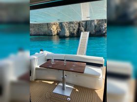 A stylish interior view of a boat's dining area featuring comfortable seating and a polished wooden table, perfect for enjoying meals while cruising on turquoise waters.