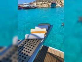 A neatly arranged set of towels on a boat deck, perfect for enjoying a day in the sun by the turquoise waters.