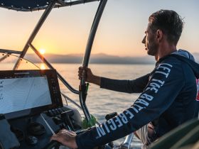 A man navigates a boat at sunset, showcasing the serene beauty of the ocean and the thrill of boating adventures.
