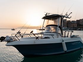 A fishing boat is docked at sunset, showcasing its sleek design and fishing gear, perfect for a day on the water.