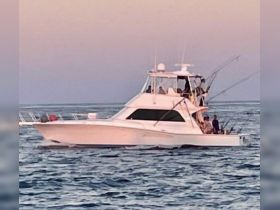 A group of anglers enjoys a fishing trip on a sleek boat, casting lines into the tranquil ocean waters during a beautiful sunset.