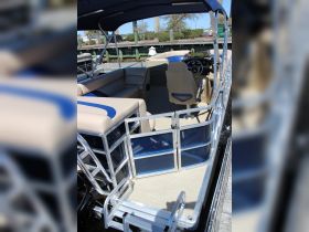 Interior view of a spacious pontoon boat featuring comfortable seating and a well-equipped helm, perfect for leisurely outings on the water.