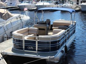 A sleek pontoon boat docked at the marina, showcasing its spacious seating and stylish design, perfect for leisurely outings on the water.