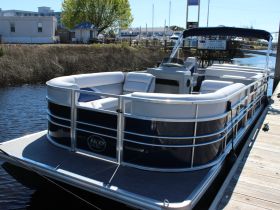 A sleek pontoon boat docked at the marina, showcasing its spacious seating and modern design — perfect for leisurely outings on the water.