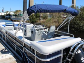Interior view of a spacious pontoon boat featuring comfortable seating and a well-equipped helm, perfect for leisurely outings on the water.