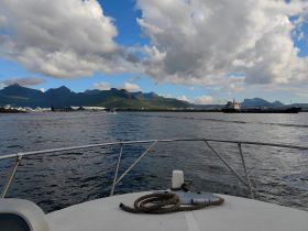 A scenic view from the bow of a boat, showcasing the stunning mountains and calm waters, perfect for exploring coastal landscapes.
