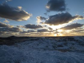 A dramatic view of turbulent ocean waves under a cloudy sky at sunset, capturing the raw beauty of nature.