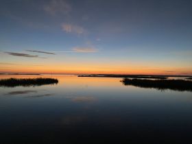 A stunning sunset reflects over calm waters, creating a serene and picturesque scene perfect for nature lovers and photographers.