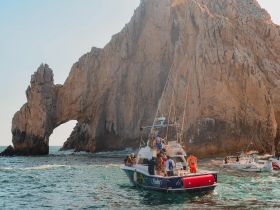 A lively group enjoys a boat trip near the iconic Arch of Cabo San Lucas, showcasing stunning scenery and a perfect day on the water.