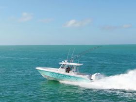 A sleek speedboat named 'Jesse James' cuts through the turquoise waters, showcasing its dynamic design and performance on the open sea.