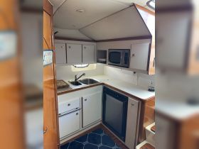 Interior view of a boat's kitchen area, featuring a sink, microwave, and storage cabinets, perfect for meal preparation while on the water.