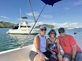 A cheerful group of friends enjoys a day on the water aboard a boat, with the 'FISH TACO' vessel visible in the background — perfect for fishing adventures and memorable outings.