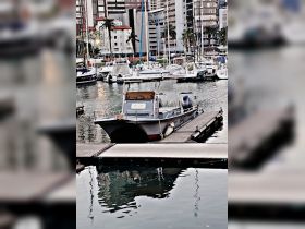 A well-maintained boat docked at a marina, reflecting the surrounding cityscape — perfect for exploring coastal waters.