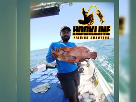 A proud angler displays a large catch aboard a fishing charter, showcasing the thrill of deep-sea fishing adventures.
