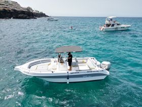 A sleek speedboat named 'White Shark' navigates the clear turquoise waters, showcasing its modern design and inviting atmosphere for a day of adventure on the sea.