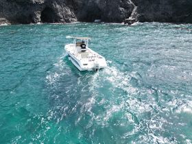 Aerial view of a speedboat navigating through clear turquoise waters, showcasing the stunning coastal scenery and perfect for adventure seekers.