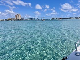 A stunning view of clear turquoise waters with a bridge and city skyline in the background, perfect for showcasing the beauty of coastal adventures.
