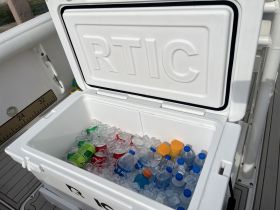 A well-stocked cooler filled with a variety of beverages and ice, perfect for keeping guests refreshed during a day on the water.