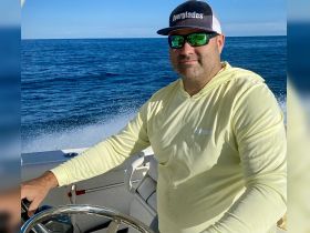 A man confidently steers a boat through the open ocean, showcasing the thrill of boating adventures on the water.