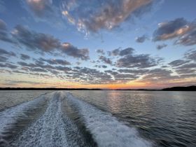 A stunning sunset reflects on the water, with beautiful clouds creating a picturesque backdrop — perfect for evening boat rides and scenic views.
