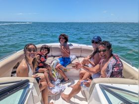 A joyful family enjoys a sunny day on the water, smiling and having fun aboard their boat — perfect for creating lasting memories together.