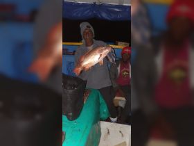 A successful night fishing trip captures a proud angler holding up a large catch, showcasing the excitement of fishing adventures with friends.