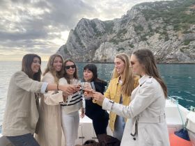 A group of friends raises their glasses in a toast aboard a boat, celebrating together against a stunning coastal backdrop — perfect for memorable outings and gatherings.