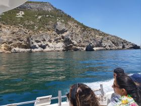 A group enjoys a scenic boat tour along a stunning coastline, capturing the beauty of nature while cruising on the water.