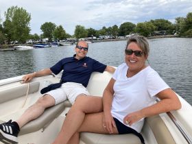 A cheerful couple enjoys a relaxing moment aboard a boat, surrounded by scenic waters and greenery — perfect for a day out with friends.