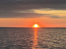 A stunning sunset over calm waters, creating a beautiful reflection — perfect for serene evening boat cruises.