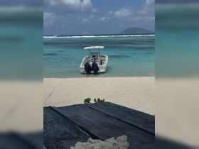 A sleek speedboat is docked in the clear turquoise waters, providing a perfect backdrop for a day of adventure on the beach.