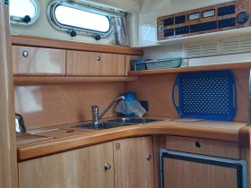 Interior view of a boat's kitchen area, showcasing wooden cabinetry and essential amenities, perfect for meal preparation while on the water.