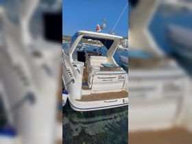 A clear view of the back of a Sealine yacht named 'Elba I' docked in a marina, showcasing its elegant design and inviting seating area.
