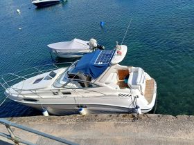 Aerial view of a sleek yacht docked in clear waters, showcasing its elegant design and solar panel features — perfect for luxury boating experiences.