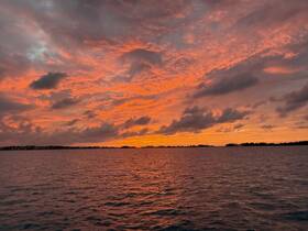 A breathtaking sunset paints the sky in vibrant hues over the tranquil waters, creating a picturesque backdrop perfect for evening boat cruises.