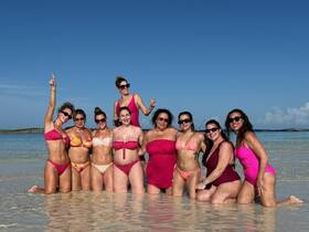 A lively group of friends celebrates together in the shallow waters of a beautiful beach, perfect for bachelorette parties or fun getaways.