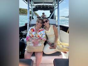 A joyful moment captured on a boat with two women smiling together, showcasing the fun and connection of family outings on the water.